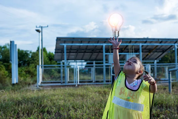 stock image A girl with the future of renewable energy and sustainable energy. holding a light bulb in their hand at the solar panel solar farm Environmentally friendly concept and pure energy.