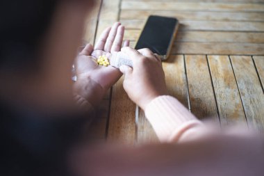 Young Asian woman holding pills in hand preparing for use The concept of taking care of one's health and helping people in the house.