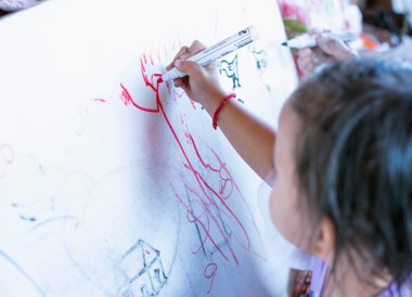 Şirin küçük bir kız dağınık bir resim çiziyor..