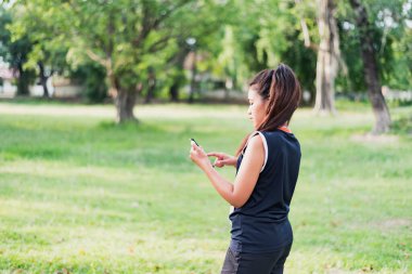 Aktif Asyalı kadın spor giysisi akıllı telefon oyunu düzenliyor. Rutin antrenmanı için hazırlanıyor. Sağlıklı yaşam tarzı, güler yüzlü spor kadını uygulama haritasında koşu rotası çiziyor.