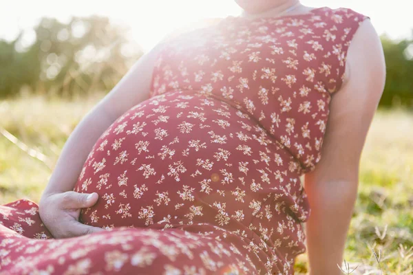 日落时分 怀孕的白人妇女在瑜伽中抱着她的腹部在公园里摆姿势 背光的场景 左边空旷的空间 — 图库照片