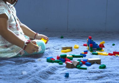 Asyalı kadın, anaokulu çocuklarının gelişimini desteklemek için plastik bloklardan bir ev inşa ediyor..