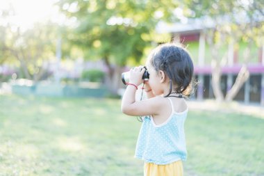 Güneşli bir günde ulusal parktaki dürbünle bakan güzel bir genç kadın..