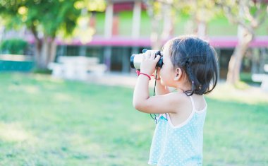 Güneşli bir günde ulusal parktaki dürbünle bakan güzel bir genç kadın..