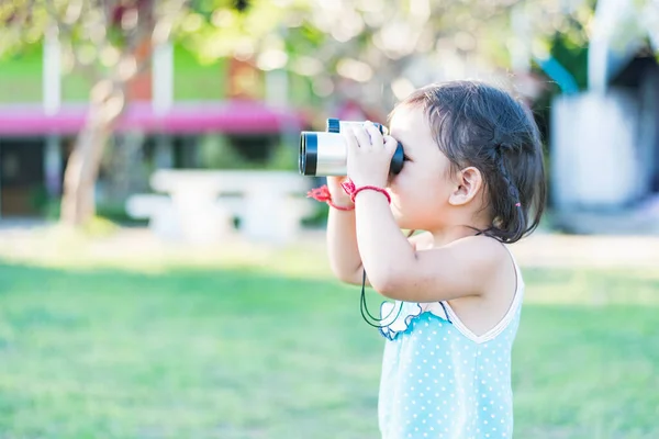 stock image Beautiful young woman looks through binoculars at the national park on a sunny day.