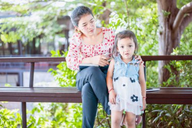 Bilgisayarlı Asyalı bir anne evden masa başında çalışıyor ve yanında küçük bir çocuk büyütüyor..