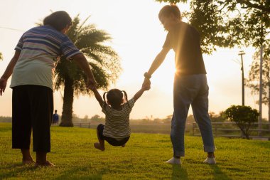 Siluet, LGBTQ ailesiyle parkta yürüyen genç kadın ve kız çeşitliliği. Aile akşamları bahçenin arkasında eğleniyor..