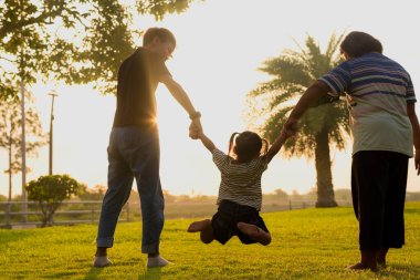 Siluet, LGBTQ ailesiyle parkta yürüyen genç kadın ve kız çeşitliliği. Aile akşamları bahçenin arkasında eğleniyor..