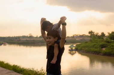 Gün batımının önünde bebeğini tutan bir annenin silüeti..