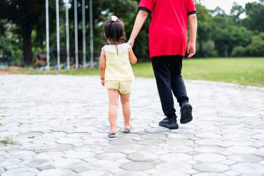 Genç bir anne küçük kızıyla parkta yürüyor. Yaz sağlığı konsepti.