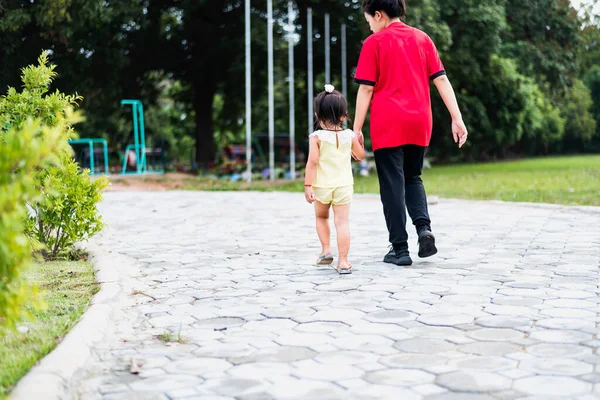 stock image A young mother is walking in the park with her little daughter. Summer health care concept.