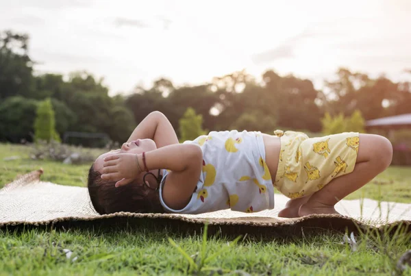 stock image girl doing gymnastics on a fitness mat lonely at home doing yoga doing bridge natural back bend Flexible kids doing gymnastic exercises. Sport, learning, fitness, stretching, active lifestyle concept.