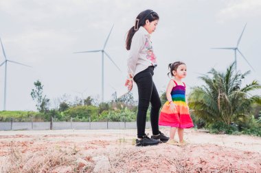 Asyalı kızlar elektrik üretmek için rüzgar türbinlerini incelerler. Sürdürülebilir enerji. gelecek.