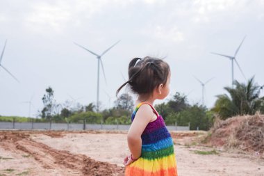 Asyalı kızlar elektrik üretmek için rüzgar türbinlerini incelerler. Sürdürülebilir enerji. gelecek.