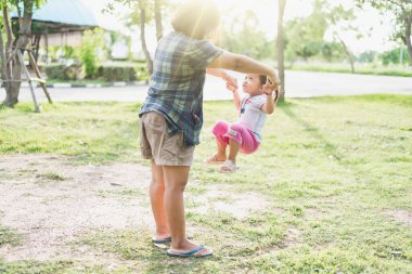 Yaz gününün doğasında mutlu bir aile. Eğlenceli ve aktif ebeveynler küçük kızlarıyla güneşin altında oynuyorlar. Havada süzülen bir kız annesinin elini tutuyor..