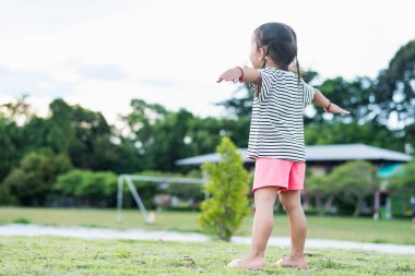 Parktaki mutlu Asyalı çocuk kollarını açmış dışarıda dinleniyor. Özgürlük kavramı.