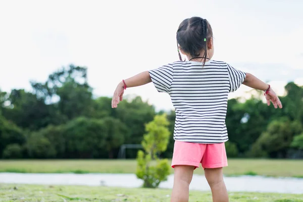 Stock image Happy Asian child in park standing with arms outstretched Young girl relaxing outdoors. Freedom concept.