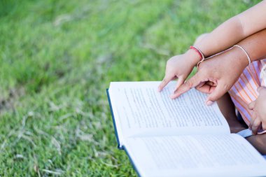 Ön bahçede kitap okuyan bir kız. Öğrenci portresi, eğitim konsepti. Öğrenirken gülümseyen sevimli çocuk..