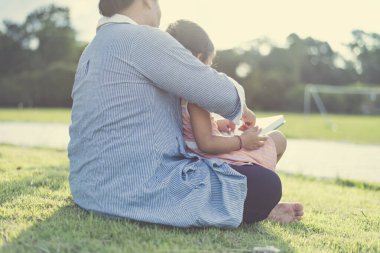 Ön bahçede kitap okuyan bir kız. Öğrenci portresi, eğitim konsepti. Öğrenirken gülümseyen sevimli çocuk..