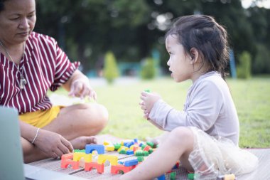 Kızı ve annesi ön bahçede legolarla oynuyorlar. Erken öğrenim ve gelişim kavramı.