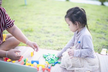 Kızı ve annesi ön bahçede legolarla oynuyorlar. Erken öğrenim ve gelişim kavramı.