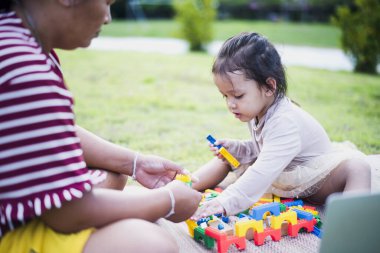 Kızı ve annesi ön bahçede legolarla oynuyorlar. Erken öğrenim ve gelişim kavramı.