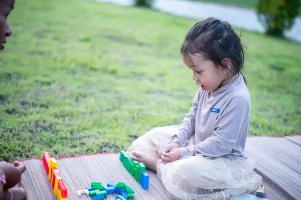 Kızı ve annesi ön bahçede legolarla oynuyorlar. Erken öğrenim ve gelişim kavramı.