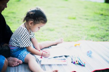 Anne ve küçük çocuk bahçede resim yapıyorlar anne ve kız doğanın resimlerini çiziyorlar..