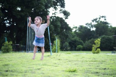 Sevimli küçük kız evde eğleniyor, etrafta koşuşturuyor ve çimlerin üzerinde zıplıyor. Mutlu çocuklar çocukluğun tadını çıkarıyor ve evde oynuyorlar..