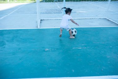 Futbol oynayan şirin bir çocuk. Çocuklar açık alanda oynuyorlar. Sevimli küçük atlet topa vuruyor Yaz sporları Aktif çocuklar için Çocuklar spor yapıyor.