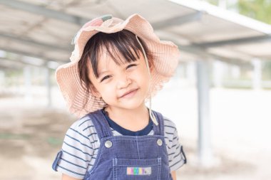 Şirin küçük kız güneş pili çiftliğinde güneş panellerinin önünde mutlu bir şekilde yürüyor..