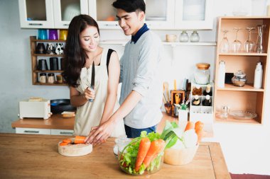 Hamile kadınlar ve çiftlerden oluşan bir aile evde yeşil sebzelerle sağlıklı bir yemek hazırlıyor..