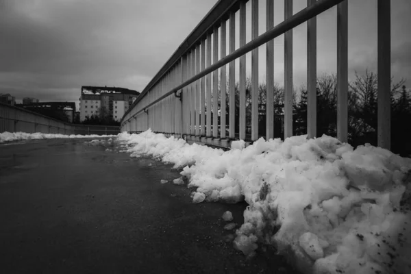snow on a bridge railing in winter in black and white