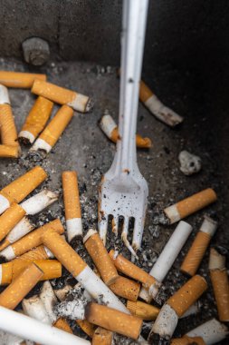 cigarette stubs with a plastic fork in a rubbish bin with view from above