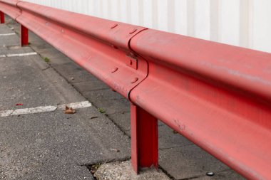 a red guardrail in a parking lot