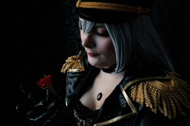 Elinde gülle siyah üniformalı baskın bir kadın.