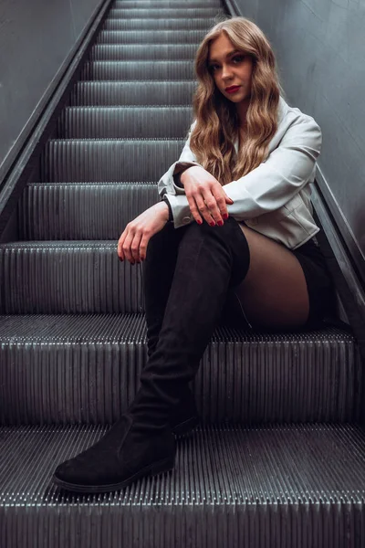 在城市的自动扶梯上坐着一个迷人的女人 — 图库照片