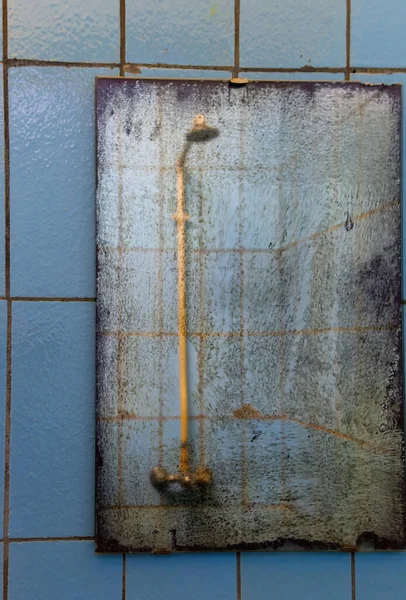 在风化的肮脏镜子中的旧淋浴器 — 图库照片