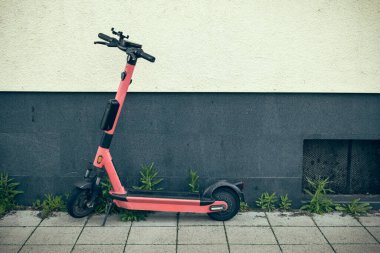 Şehirdeki bir ev duvarında bir e-scooter.