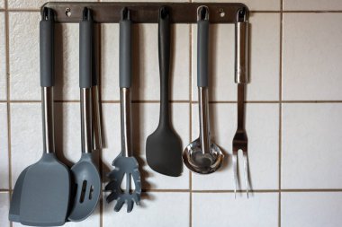 Mutfakta fayansların önünde mutfak aletleri var.