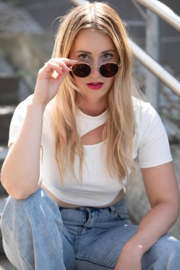 Beyaz bluzlu ve güneş gözlüklü güzel bir kadın.