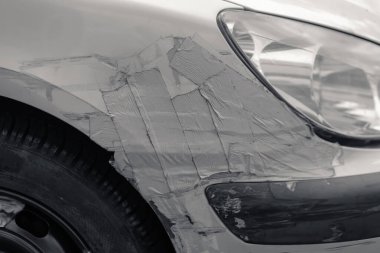 Siyah beyaz bir kazadan sonra zırh bandıyla bantlanmış bir araba.