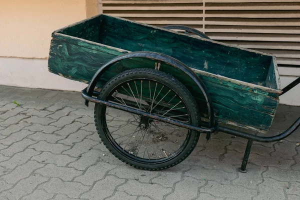 stock image a green old bicycle trailer on a sidewalk