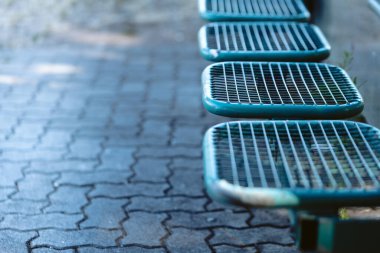 Şehirdeki bir otobüs durağında mavi koltuklar seçici bir odak noktasında.