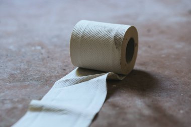 Seçici bir odak noktasında yere yuvarlanmış eski bir tuvalet kağıdı.