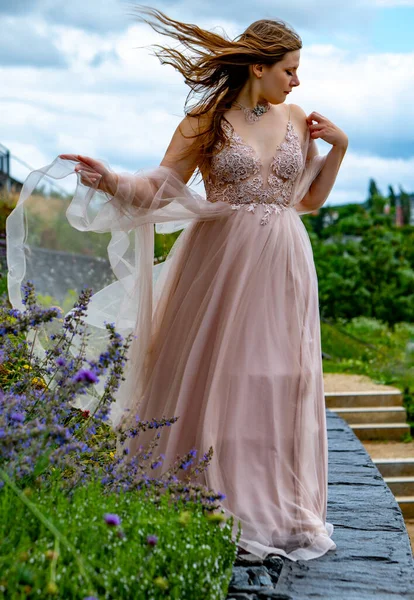a beautiful woman in pink dress in the wind