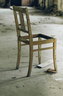 Eski, kirli, kırık bir tahta sandalye kayıp bir yerde.
