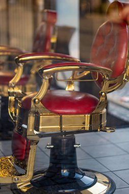 Berber dükkanının camından içeri giren eski kırmızı berber sandalyesi.
