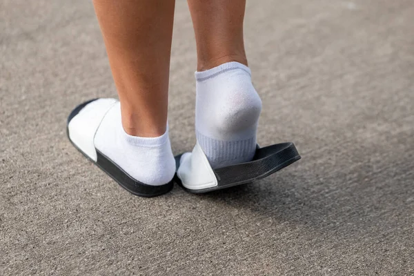 a woman with white socks and sandals in summer walking on the street