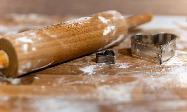 a rolling pin with flour and cookie molds in the kitchen